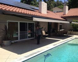 woman standing under an awning by her pool