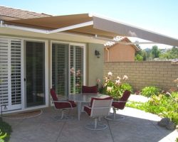 Small concrete patio with a table and chair set under a retractable awning